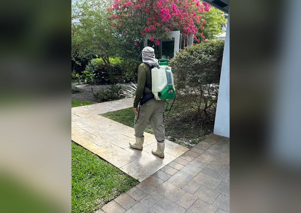 A Non-Stop technician with a backpack sprayer walking a home's front walkway