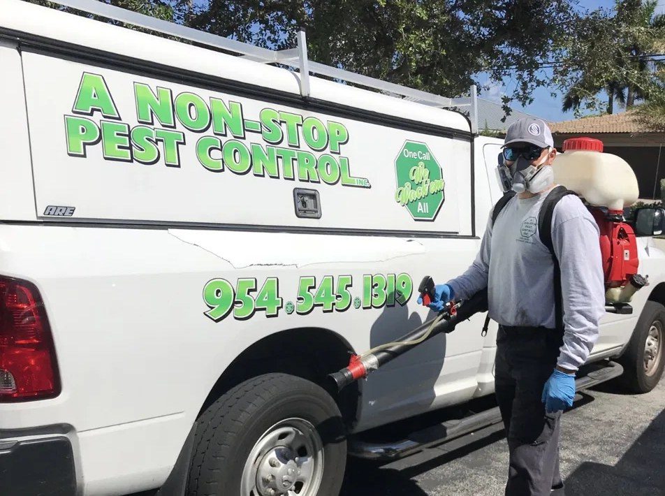 A Non-Stop technician with a backpack mosquito sprayer next to the company truck